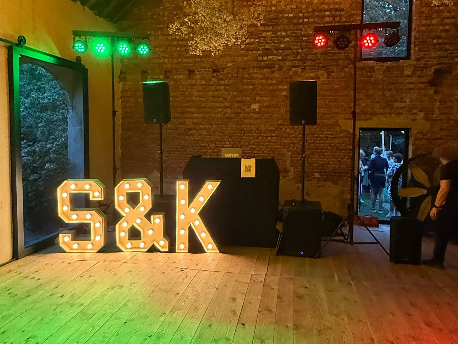 Lichtletters S&K voor de DJ-set in een bakstenen schuur met groen en rood licht